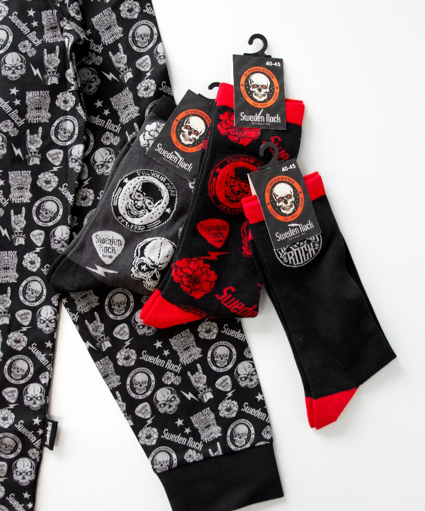 Färjestad BK merchandise utlagd på en gräddvit hoodie: ett vit- och grönfärgat golfklubbsfodral, en randig mugg, ett litet snapsglas i metall och ett par randiga strumpor